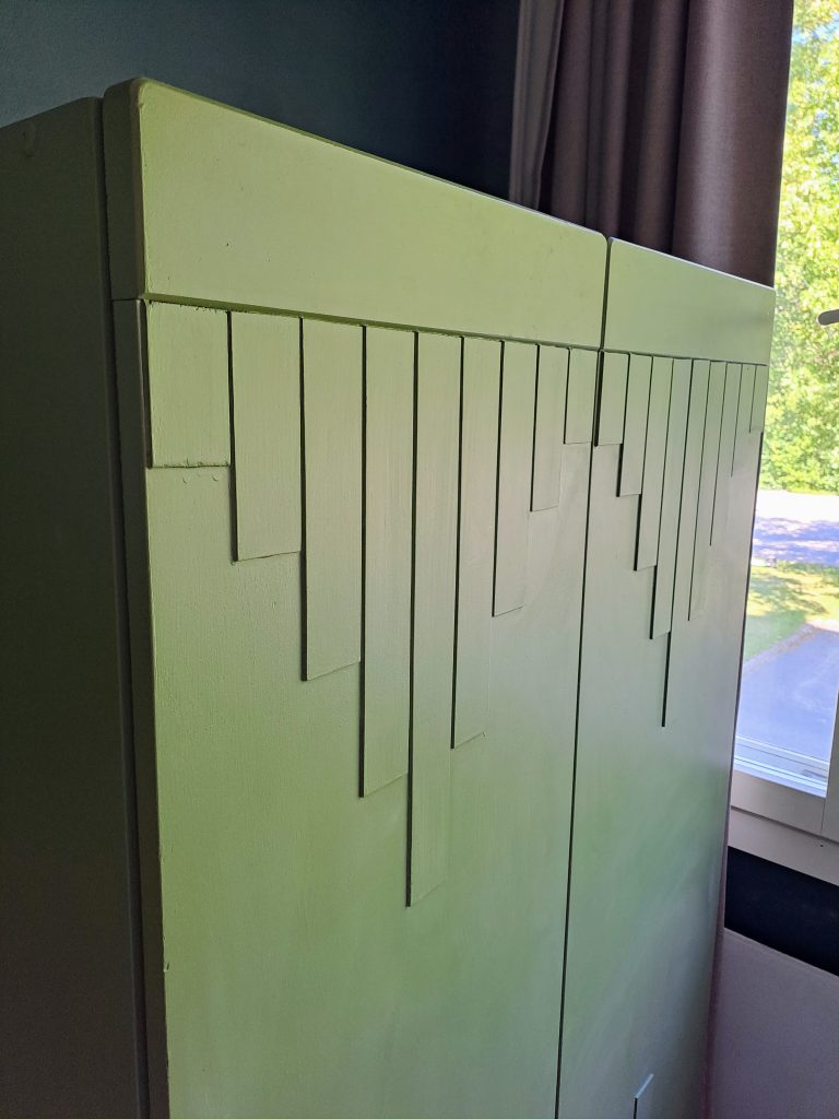 kuva työkaapin etuosasta. Ovissa inka-henkistä panelointia